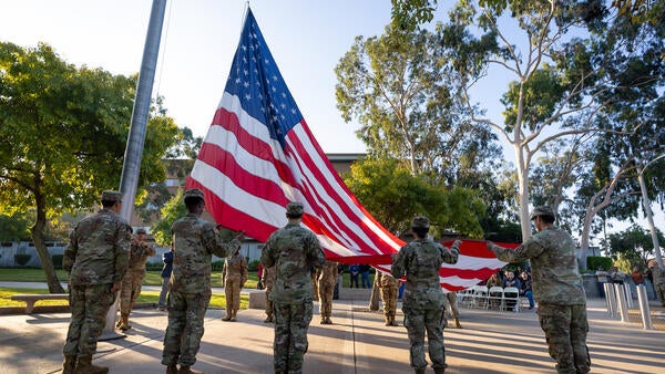 A group of people in military uniforms perform a raising of the American flag ceremony.